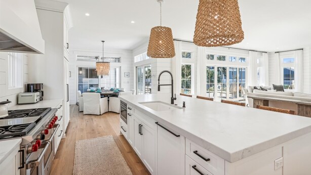 A modern kitchen with white cabinetry, a large island, and a dining area. - Spacious Home w/ Pool & Short Trip to the Beach (Hilton Head Island)