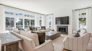 A spacious living room with a fireplace, large windows, and a flat-screen TV. - Spacious Home w/ Pool & Short Trip to the Beach (Hilton Head Island)