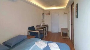 A small, well-lit room with a bed, a desk, a chair, and a door. - The Reef Diving Resort 海景雙人房b (Taitung County)
