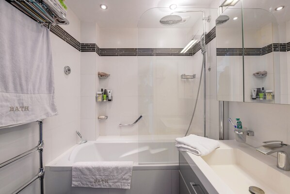 A modern bathroom with a glass-enclosed shower, a bathtub, and a vanity with a mirror.