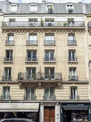 A multi-story building with balconies, a storefront, and a sign for 'Arnaud Larher'.