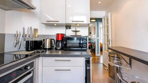 A modern kitchen with stainless steel appliances, a coffee maker, and a microwave. There are cabinets and a countertop with utensils.