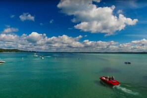 A clear view of a turquoise sea with a red boat in the foreground and several smaller boats in the distance. - NEW Bellaire Home, 5 Minute WALK to downtown! (Bellaire)
