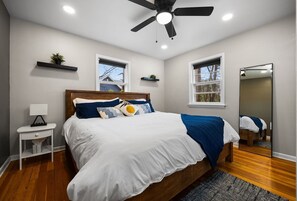 A bedroom with a bed, a nightstand, a ceiling fan, a window, and a mirror. - NEW Bellaire Home, 5 Minute WALK to downtown! (Bellaire)