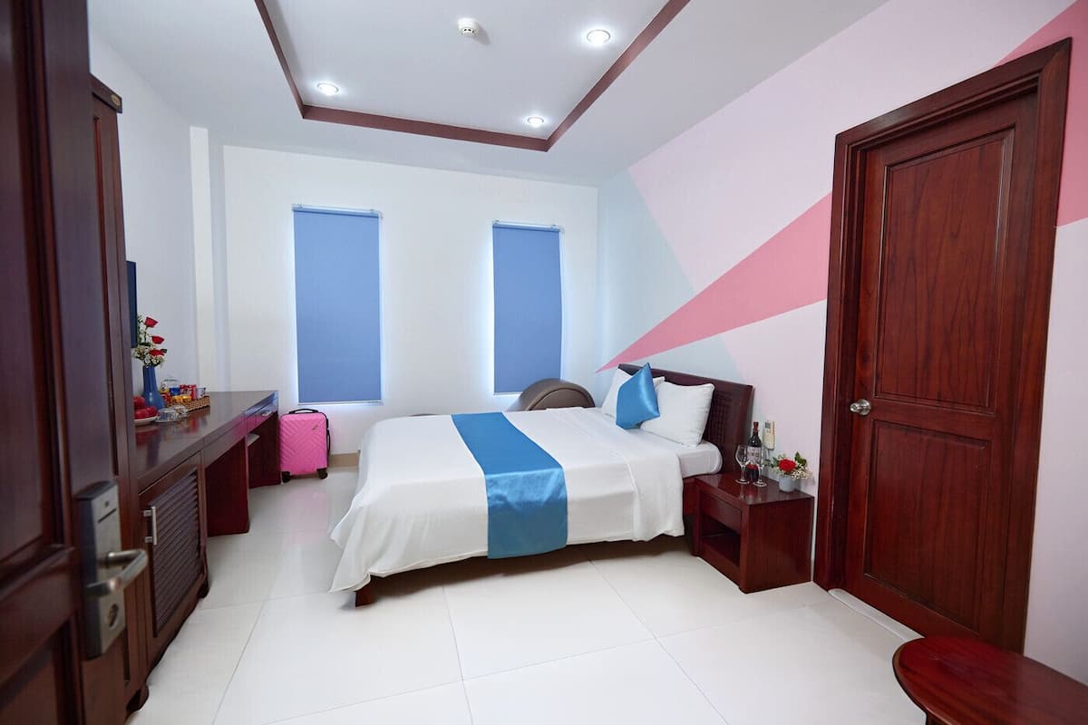 A hotel room with a bed, bedside table, and a suitcase.
