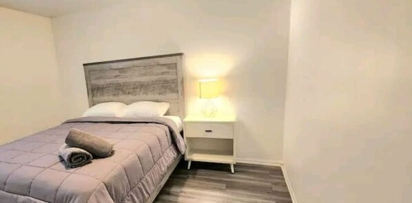 Una camera da letto con un letto, un comodino con una lampada e una testiera in legno.