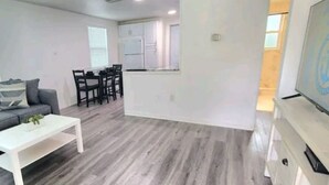 A modern living room with a gray sofa, a white coffee table, and a dining area with a table and chairs. - #13 Clearwater airport home (Clearwater)