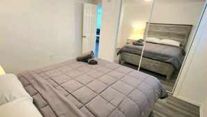 A bedroom with a bed, a bedside lamp, and a mirror reflecting the bed. - #13 Clearwater airport home (Clearwater)