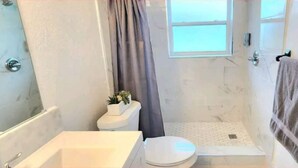 A compact bathroom with a shower, toilet, and sink. - #13 Clearwater airport home (Clearwater)