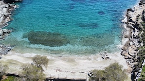 Un paisaje costero con aguas azul turquesa, acantilados rocosos y una playa de arena.