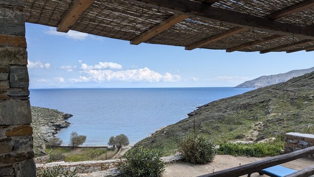 Un balcón de piedra con vistas al mar y una estructura de tejado de paja.