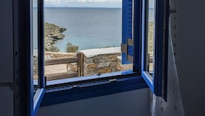 Una ventana con vistas al mar y a la costa rocosa.