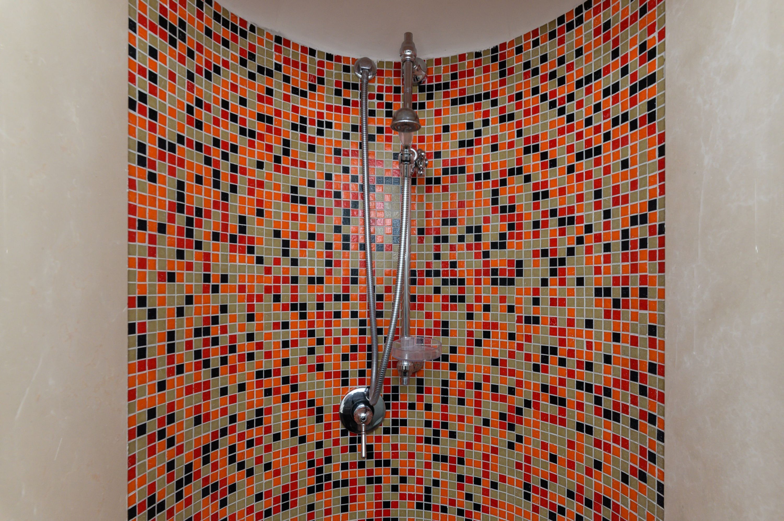 Una doccia con un muro rivestito di piastrelle a motivo geometrico.