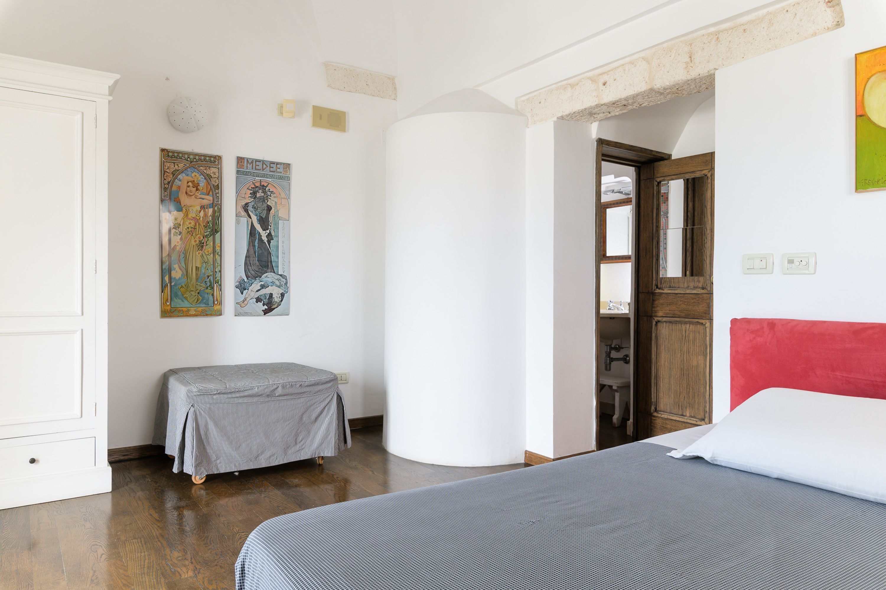 A bedroom with a bed, a bench, and two wall-mounted artworks.