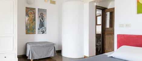 A bedroom with a bed, a bench, and two wall-mounted artworks.