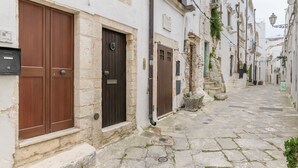 A narrow cobblestone street flanked by white buildings with wooden doors and stone steps. - Terrazza Olivia Maria by Wonderful Italy (Ostuni)