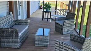 A covered outdoor deck with wicker furniture and a small table.