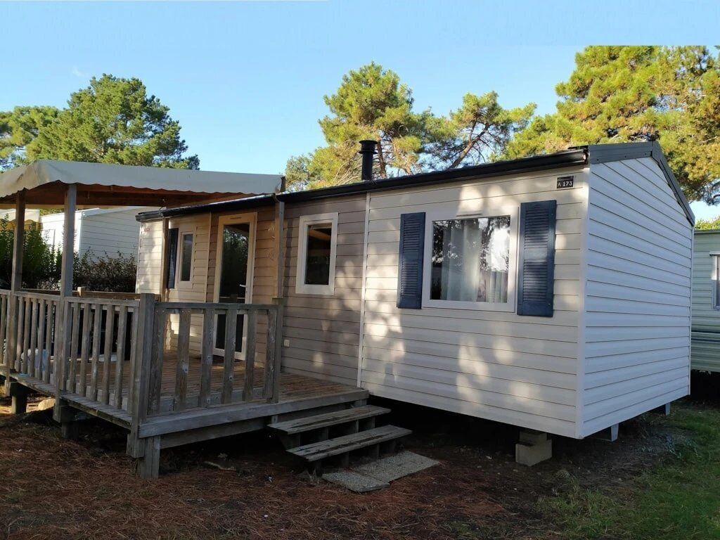Uma casa móvel térrea com um deck de madeira e varanda coberta.