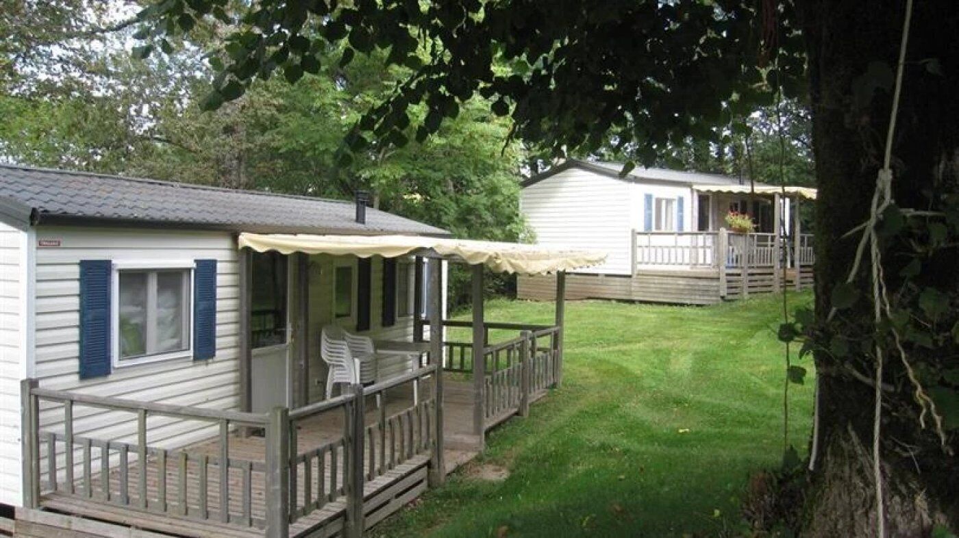 A row of mobile homes with wooden decks and a grassy yard.