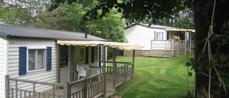 A row of mobile homes with wooden decks and a grassy yard.