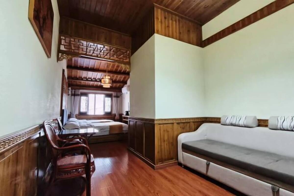 A room with wooden flooring, a sofa, a bed, and a wooden ceiling.