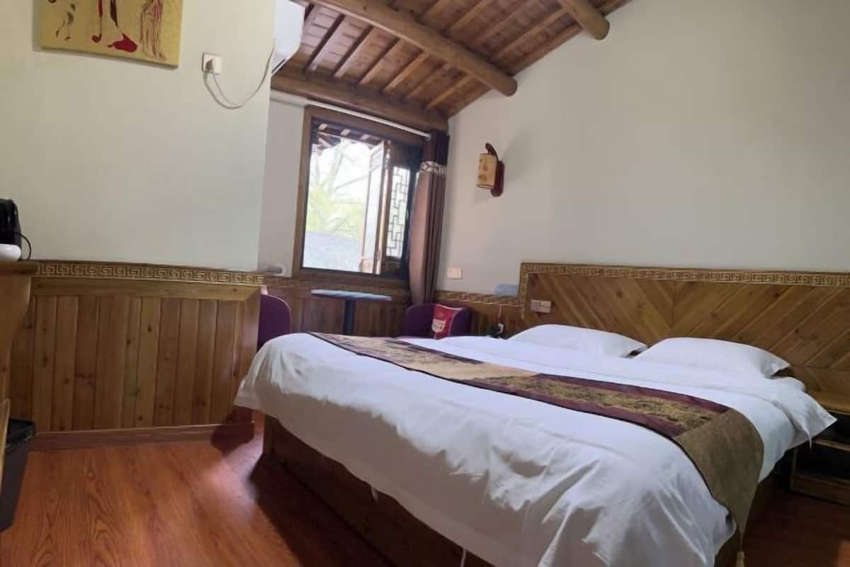 A wooden-paneled room with a bed, a small table, and a window.