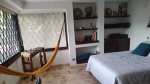 A bedroom with a bed, a hammock, a desk, and shelves with various items. - Espectacular Casa - Hotel Boutique Cartagena - Barrio Castillogrande (Cartagena de Indias)
