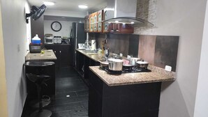A compact kitchen with a central island, black tiled flooring, and a clock on the wall. - Espectacular Casa - Hotel Boutique Cartagena - Barrio Castillogrande (Cartagena de Indias)