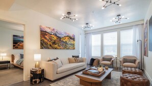 A modern living room with a sofa, armchairs, a coffee table, and a large painting. - Luxury Downtown 2 Bd 2 Ba Suite - Rooftop Terrace, Steps to Delta Center & More! (Salt Lake City)