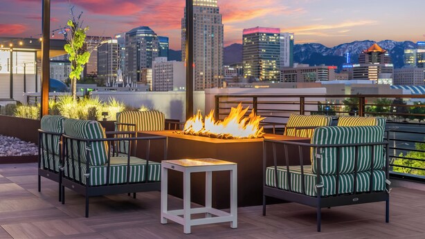 A rooftop patio with a fire feature, seating, and a city skyline view. - Luxury Downtown 2 Bd 2 Ba Suite - Rooftop Terrace, Steps to Delta Center & More! (Salt Lake City)