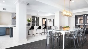 A modern kitchen with a central island, black bar stools, and a glass dining table with chairs. - Luxury Downtown 2 Bd 2 Ba Suite - Rooftop Terrace, Steps to Delta Center & More! (Salt Lake City)