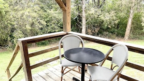 A wooden deck with a round table and two wicker chairs.