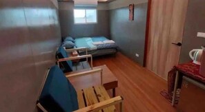 Une petite pièce comprenant un lit, une petite table et une chaise.