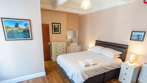 A bedroom with a bed, bedside tables, a dresser, and a mirror.