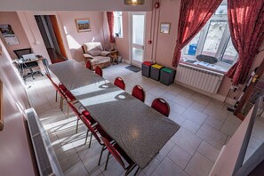 Un comedor con una mesa larga, sillas, un sofá, un radiador y una ventana con cortinas.