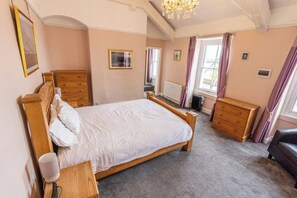 Un dormitorio con cama de madera, cómoda, aparador y radiador.