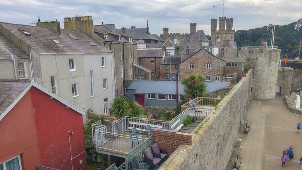 A courtyard with a stone wall, a red building, and a castle in the background.