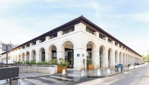 Un grand bâtiment à la façade symétrique, doté de nombreuses arcades et d’une entrée centrale.