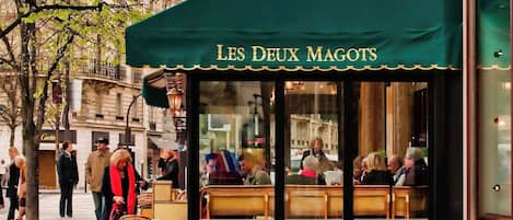 A café named "Les Deux Magots" with outdoor seating and a view of the street.