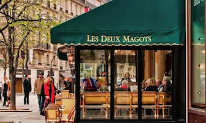 Un café appelé « Les Deux Magots », doté d’une terrasse et offrant une vue sur la rue.