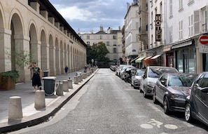Une rue bordée de voitures garées et une rangée de bâtiments, avec un hôtel situé sur le côté droit.