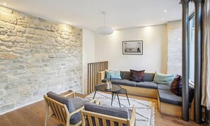 Ein Wohnzimmer mit Steinwand, einer Sofagarnitur, einem Couchtisch und einer Pendelleuchte.