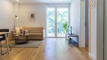 A modern living room with a sofa, coffee table, and a dining area.