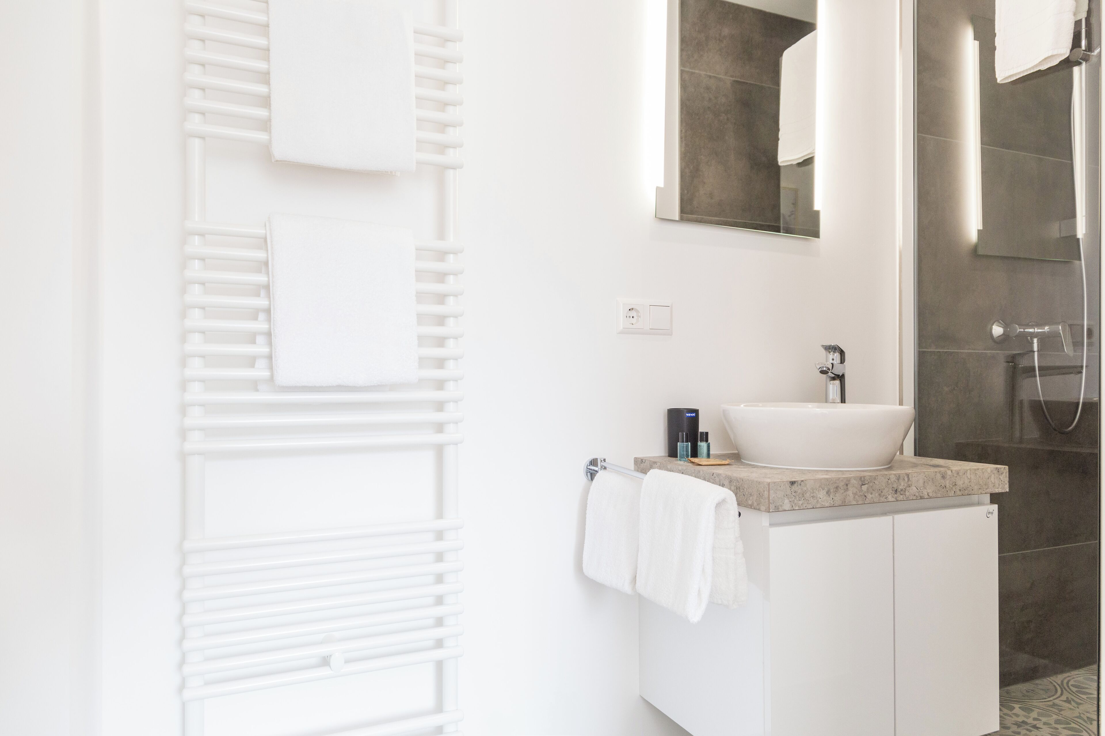 A modern bathroom with a white vanity, a large mirror, and a shower area.