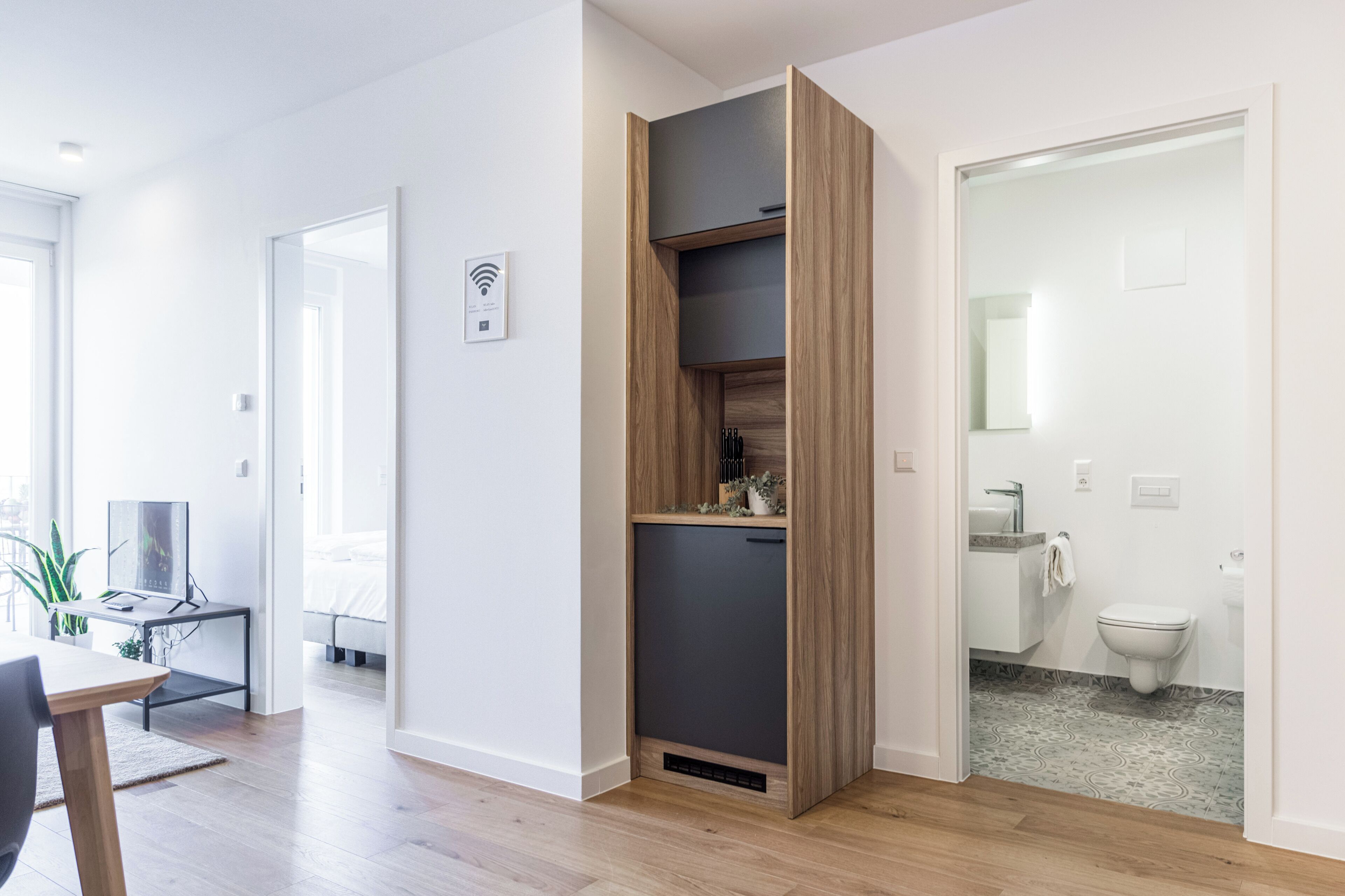 Eine moderne Wohnung mit einer Holzregal, einem Essbereich mit Tisch und Stühlen sowie einem Badezimmer mit Toilette und Waschbecken.