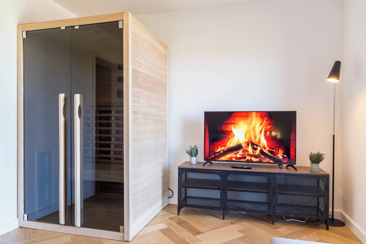 Una sala de estar moderna con chimenea, televisor y lámpara de pie.