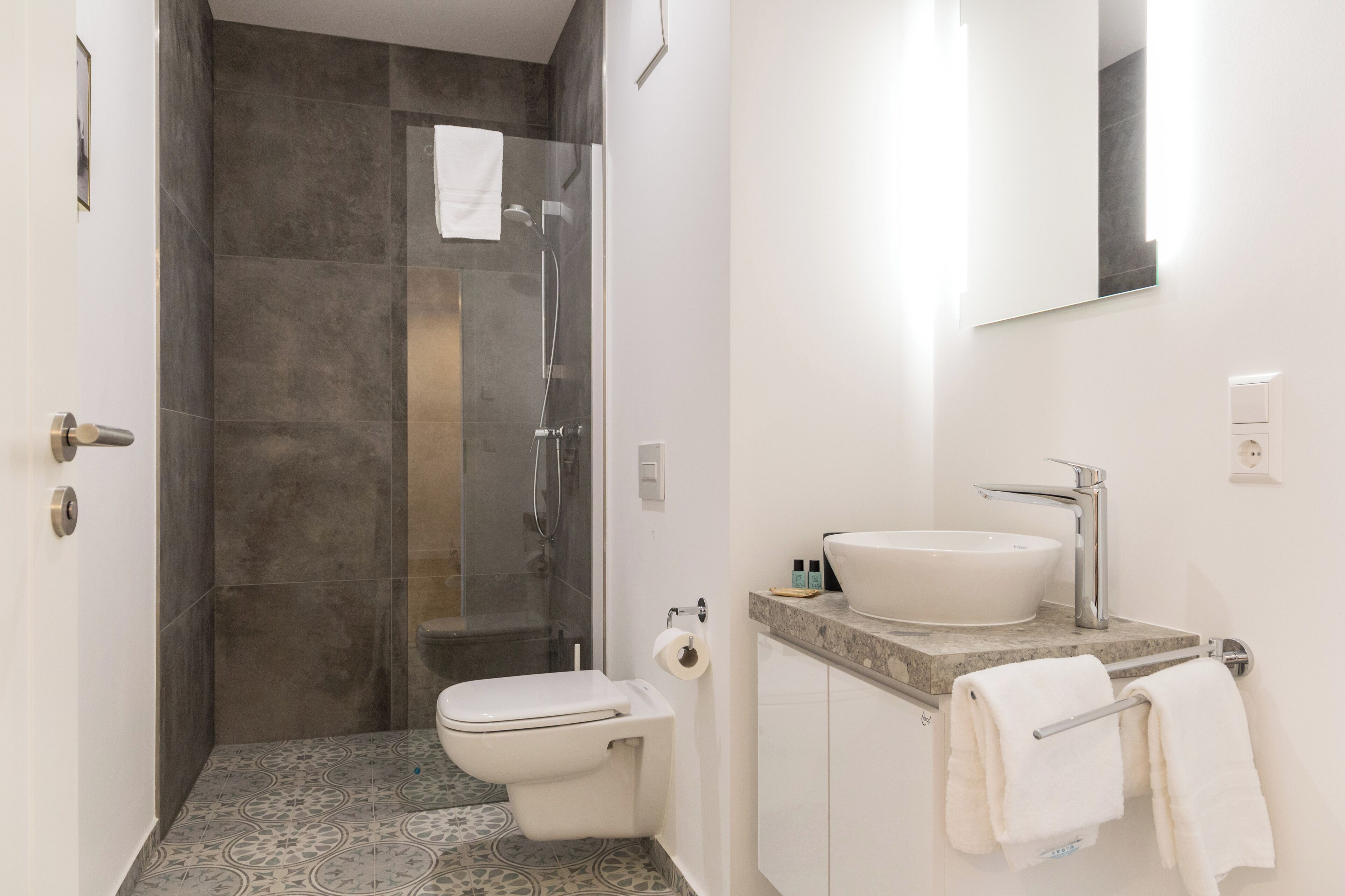 A bathroom with a shower, toilet, sink, and towel rack.