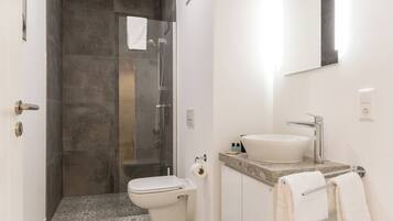 A bathroom with a shower, toilet, sink, and towel rack.