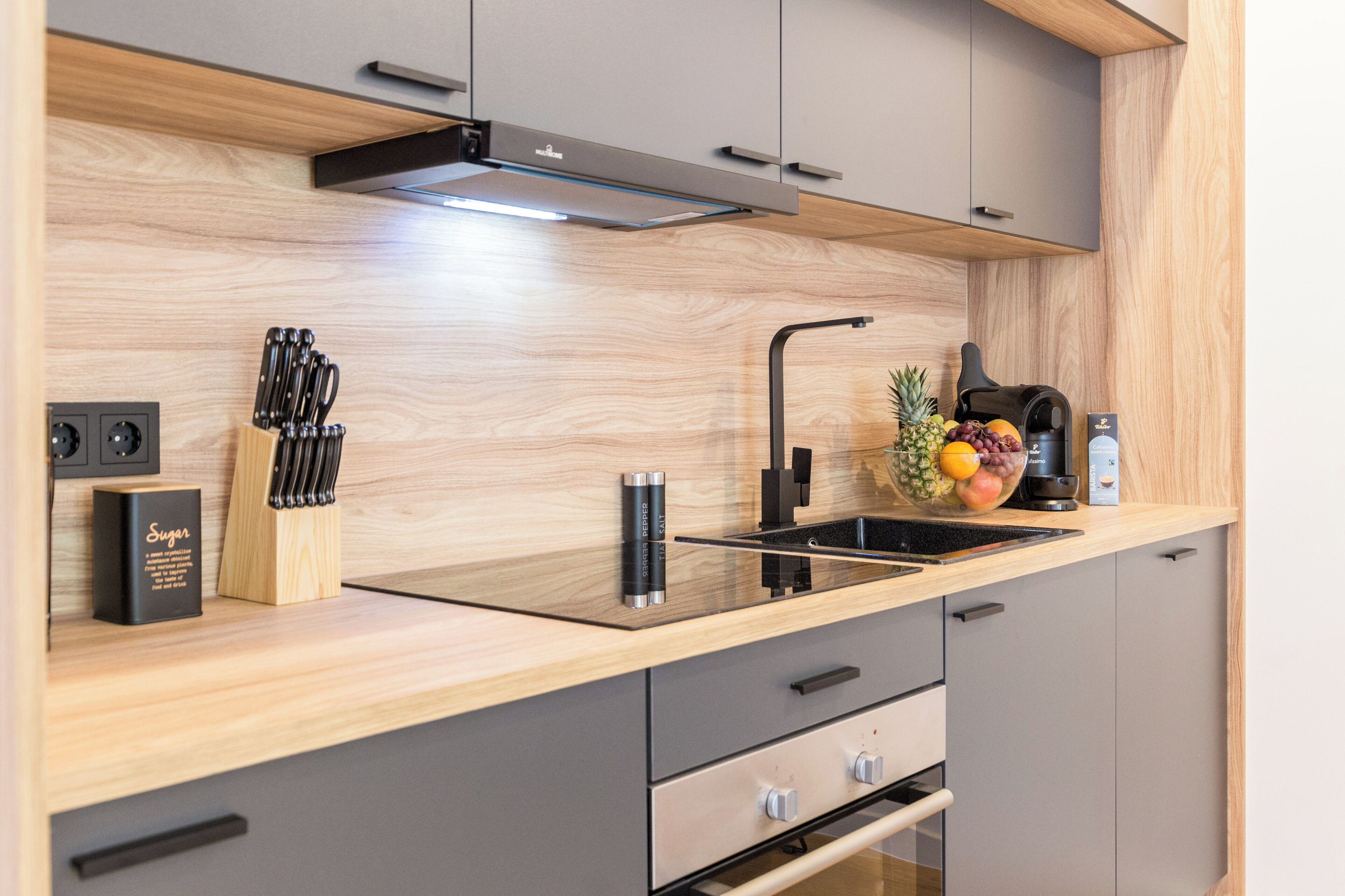 Una cocina moderna con encimera de madera, estufa integrada y un frutero.