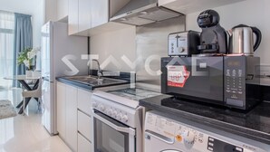 A modern kitchen with a built-in oven, microwave, and coffee maker. - Staycae Holiday Homes - Carson Tower (Dubai)